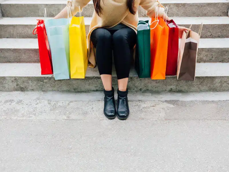 Mujer sujetando bolsas de compra en una escalera, después de seguir las recomendaciones y consejos para el Black Friday 2024