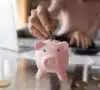 Persona introduciendo el dinero ahorrado en una hucha de cerdito