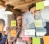 Equipo de trabajo de hombres y mujeres en una pizarra con post-it mirando cómo invertir en startups