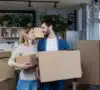 Pareja de mujer y hombre con cajas de mudanza en su nuevo hogar, gracias a Mi Primera Vivienda en Galicia