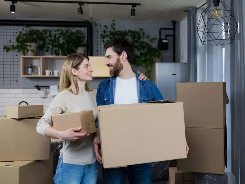 Pareja de mujer y hombre con cajas de mudanza en su nuevo hogar, gracias a Mi Primera Vivienda en Galicia