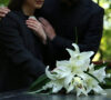 Mujer y hombre de luto, abrazándose frente a un ataúd, preguntándose cuánto cuesta un entierro