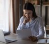 Mujer joven mirando unos papeles, revisando que debe hacer la declaración de la renta si está cobrando el paro